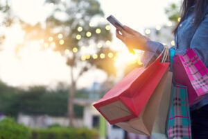 woman with phone and shopping bags on arm