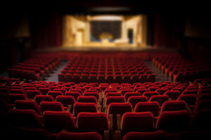 empty theater with rows of red chairs
